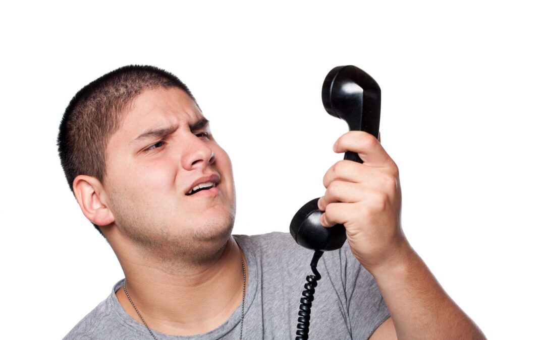 Perplexed man holding a phone receiver with a skeptical expression, embodying a customer's confusion when navigating through automated phone trees
