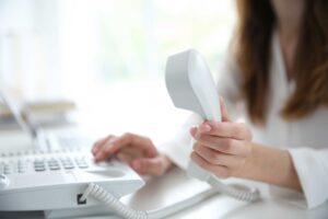 Dedicated customer service representative at a bright workstation holding a phone receiver, symbolizing the personalized touch of live answering services